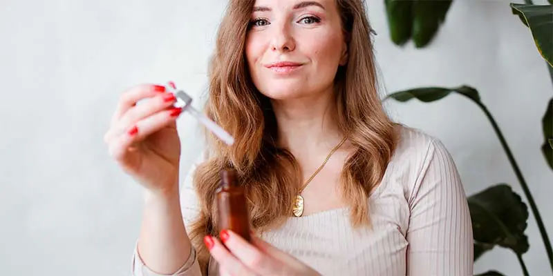 Mujer con un cuentagotas en mano a punto de utilizar un aceite cosmético