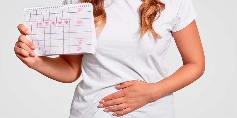 Mujer sujetando un calendario de lo que parece un ciclo menstrual