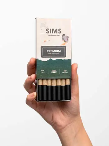 Caja de cigarrillos de CBD SIMS sujetada por una mano